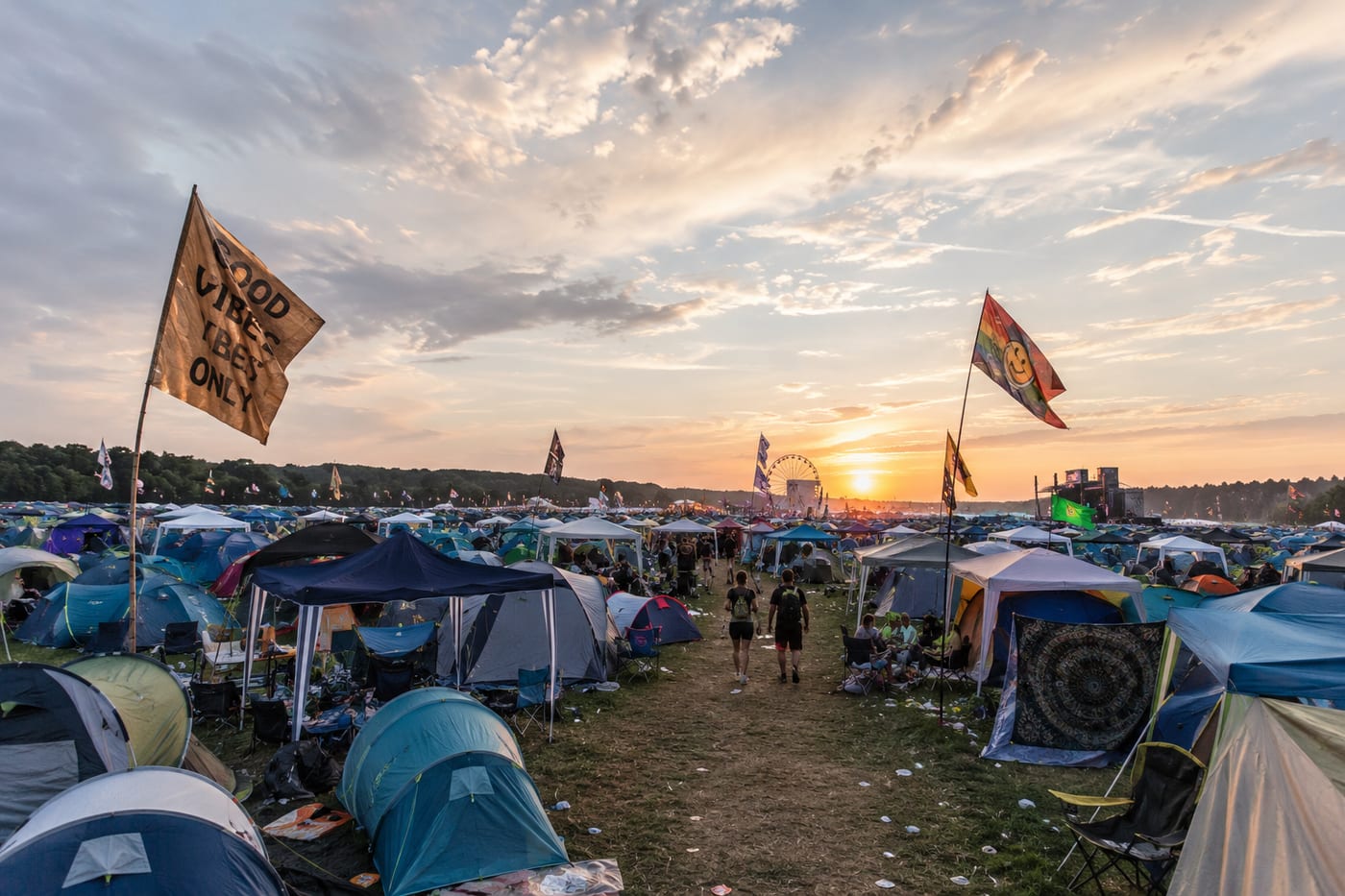 Festival-Campingplatz bei Sonnenuntergang mit Zelten, Flaggen und Riesenrad